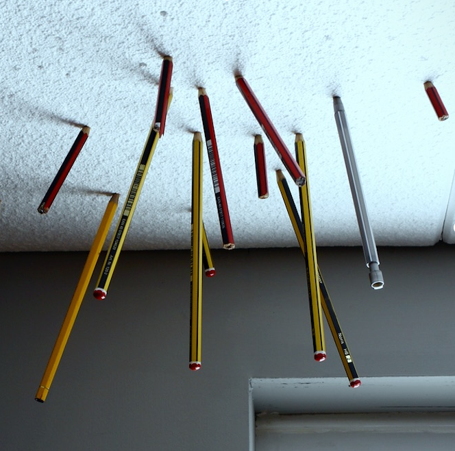 A photo of pencils stuck in bland Styrofoam office ceiling tiles.