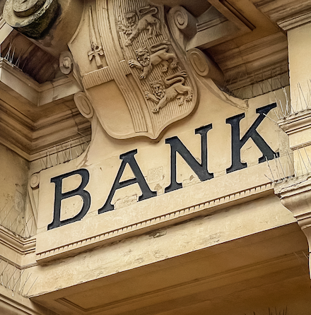 The stone facade of a British bank, with ornate scrollwork and the word 