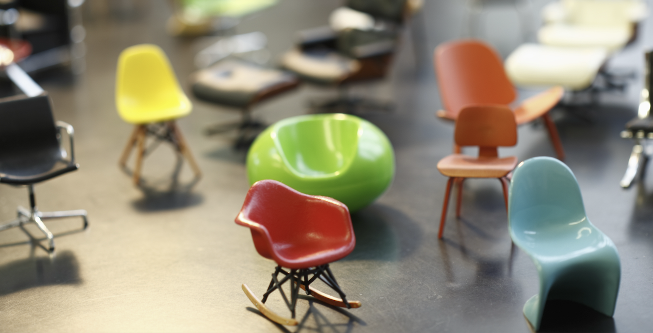 A collection of miniature designer chairs in swooping shapes and bright colors.
