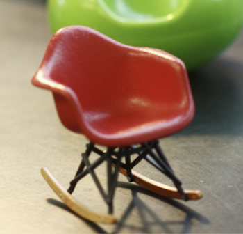 A collection of miniature designer chairs in swooping shapes and bright colors.