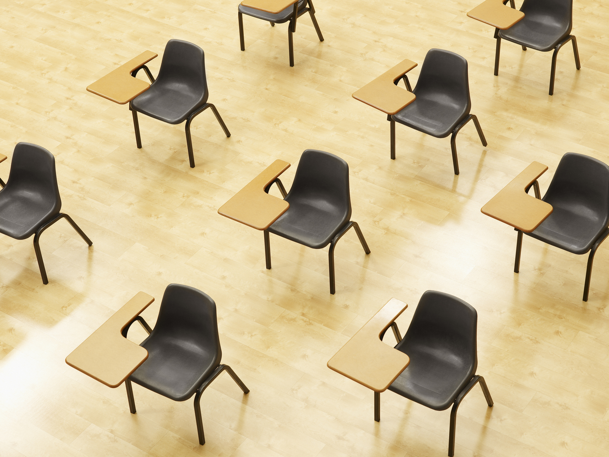 Rows of desks line up diagonally in an empty classroom.